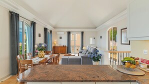 Una cocina moderna con encimeras de granito, un comedor con sillas de madera y una sala de estar con sofá y mesa de centro.