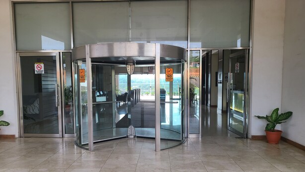 A revolving door with glass panels and a "No Firearms" sign. - Agulu Lake Resort and Conference Centre (Adazi Nnukwu)