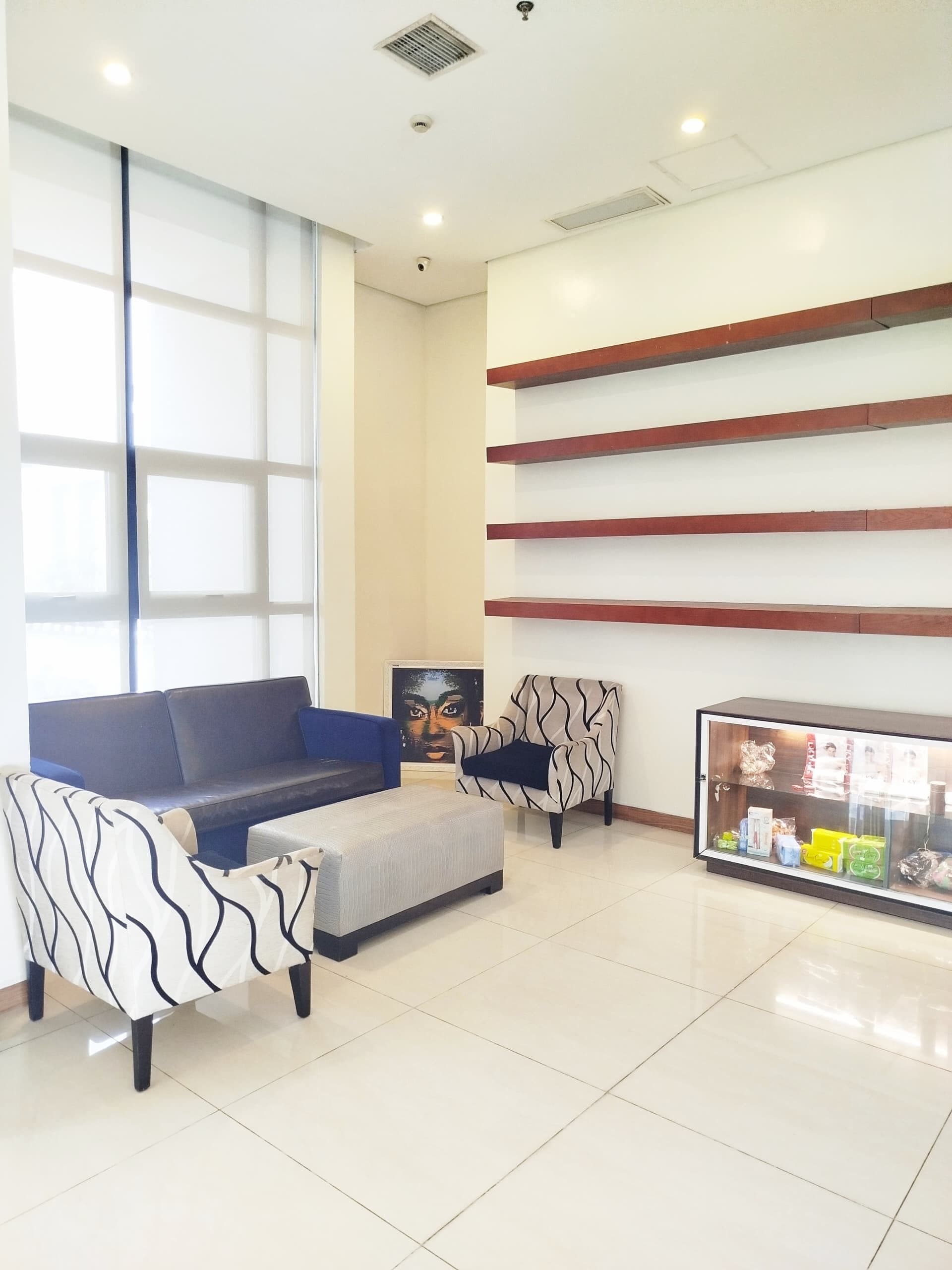 A modern lobby with a sofa, armchair, and a display cabinet.