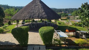A thatched-roof pavilion with outdoor seating, surrounded by well-maintained hedges and a paved walkway. - Agulu Lake Resort and Conference Centre (Adazi Nnukwu)