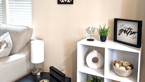 A living room with a sofa, a small table, a bookshelf, and decorative wall pieces.