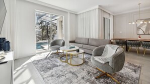 Una sala de estar moderna con un sofá, dos sillones, una mesa de centro y un comedor con mesa y sillas.