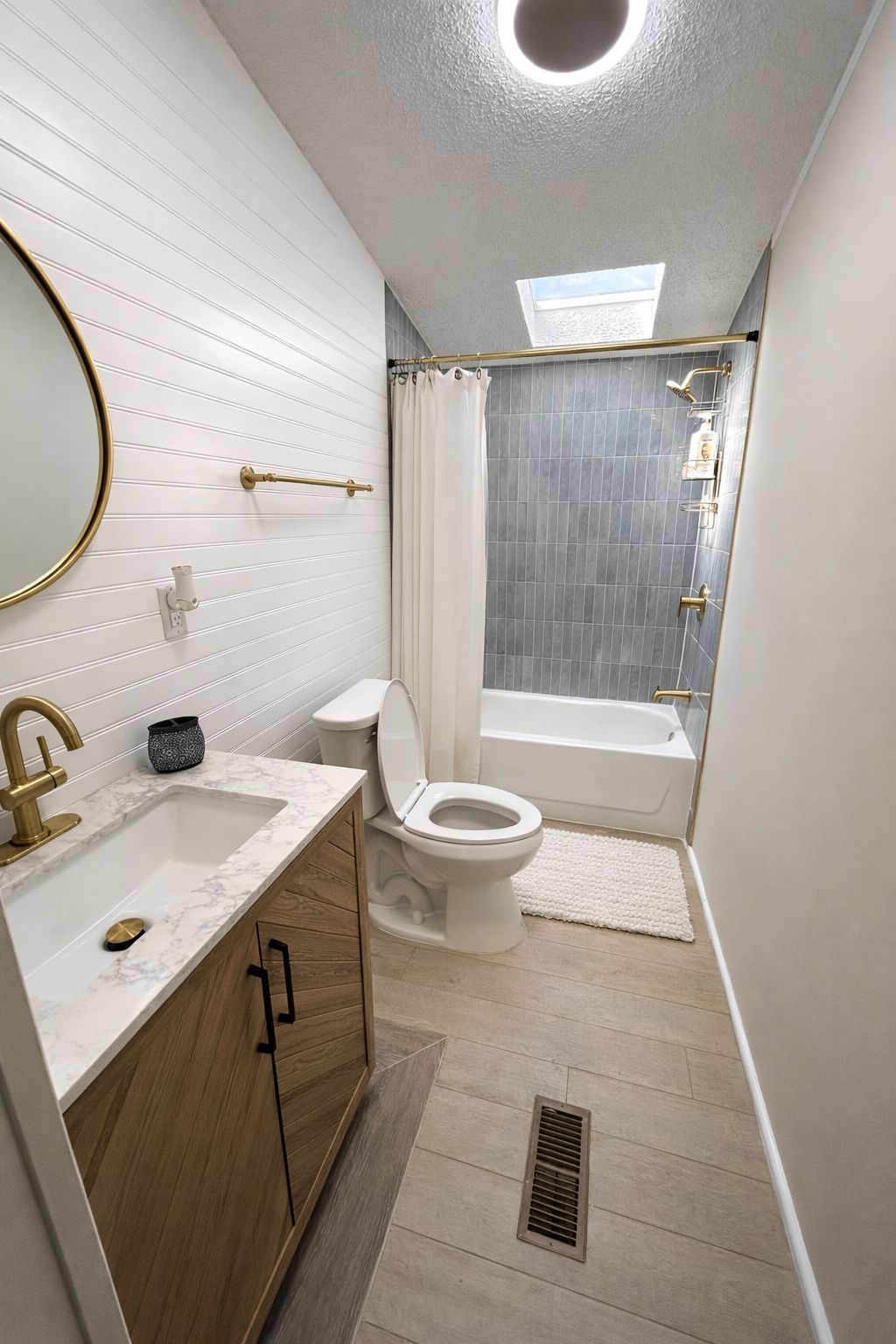 A bathroom with a white sink, gold fixtures, a toilet, and a shower area.
