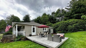Ein eingeschossiges Haus mit einer Terrasse, einem Patio mit Stühlen und einer amerikanischen Flagge.