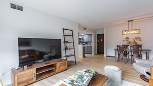 Un salon moderne avec un téléviseur à écran plat, un meuble de rangement en bois et un magazine posé sur une table basse.