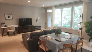 A modern living room with a sofa, TV, dining table, and large windows. - Charming 3-bedroom home with AC, WiFi and a sofa bed in fantastic Calgary (Calgary)