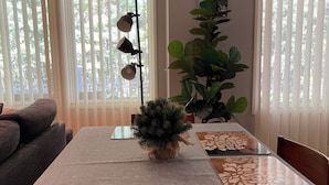 A dining area with a table set for four, a potted plant, and a wall-mounted lamp. - Charming 3-bedroom home with AC, WiFi and a sofa bed in fantastic Calgary (Calgary)