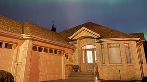 A house with a garage, a front porch, and a stone facade. - Charming 3-bedroom home with AC, WiFi and a sofa bed in fantastic Calgary (Calgary)