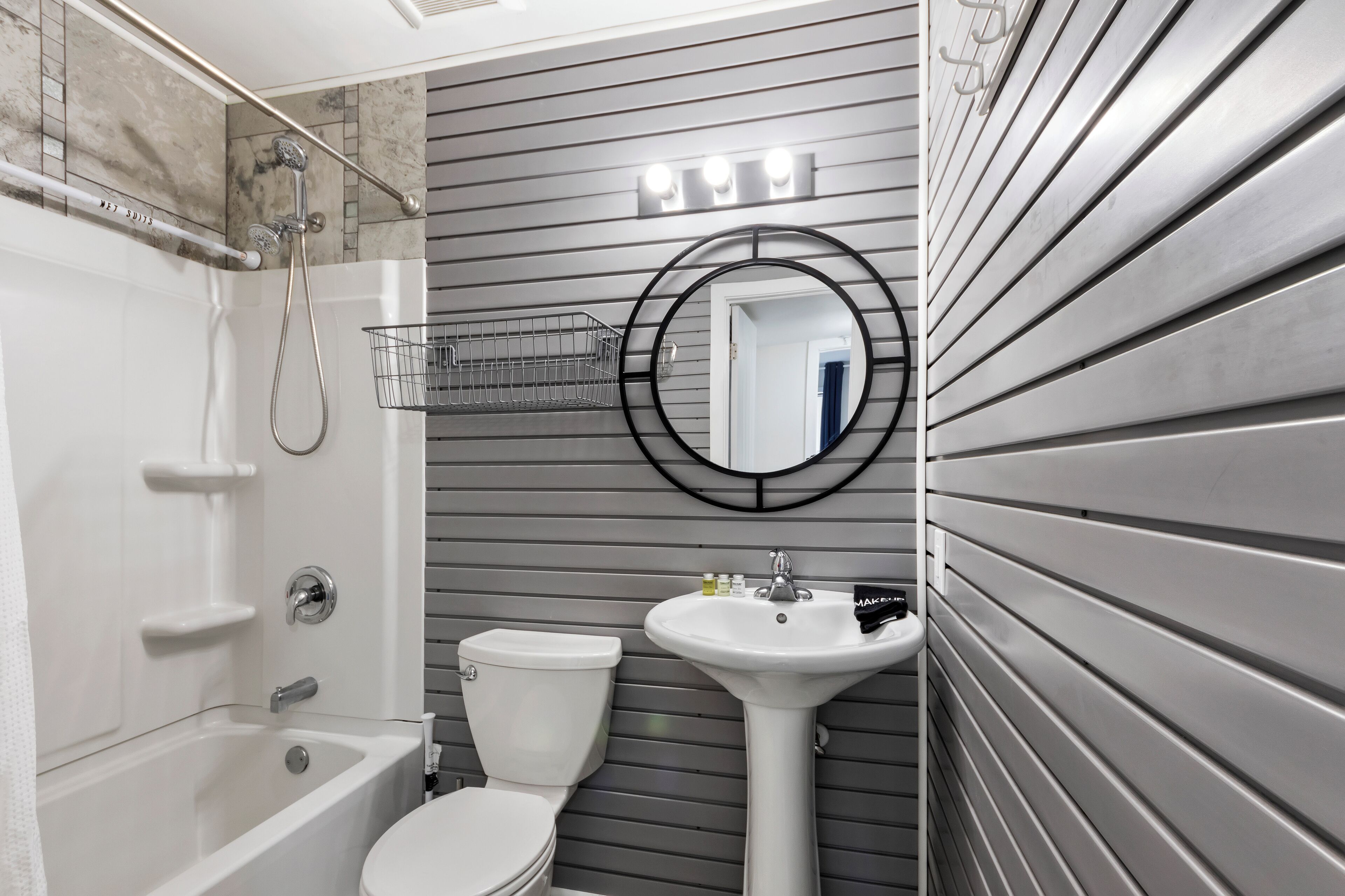 Un baño moderno con bañera, inodoro, lavamanos y un espejo con iluminación.