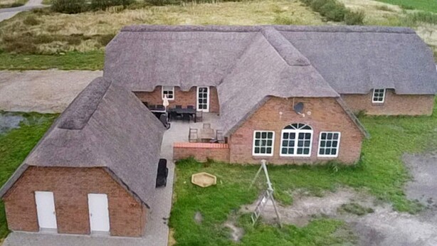 A large house with a thatched roof, multiple windows, and a paved driveway. - 4 Star Holiday Home in Ulfborg (Ulfborg)