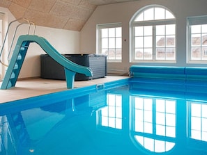 An indoor swimming pool with a blue slide, large windows, and a tiled ceiling. - 4 Star Holiday Home in Ulfborg (Ulfborg)