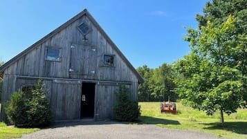 Une grange rustique en bois, dotée d’un toit triangulaire et d’une petite fenêtre à l’étage supérieur.