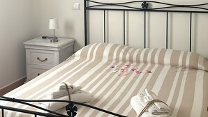 Una cama bien hecha con ropa de cama a rayas, una mesita de noche con lámpara y un cuadro en la pared.