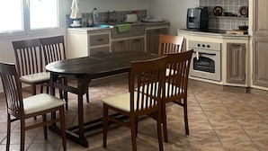 Una cocina compacta con una mesa y sillas, horno empotrado y cafetera.