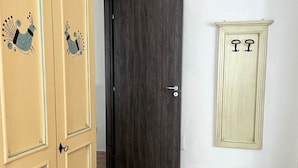 Una habitación con piso de baldosas, una puerta de madera oscura y un armario claro con detalles decorativos.