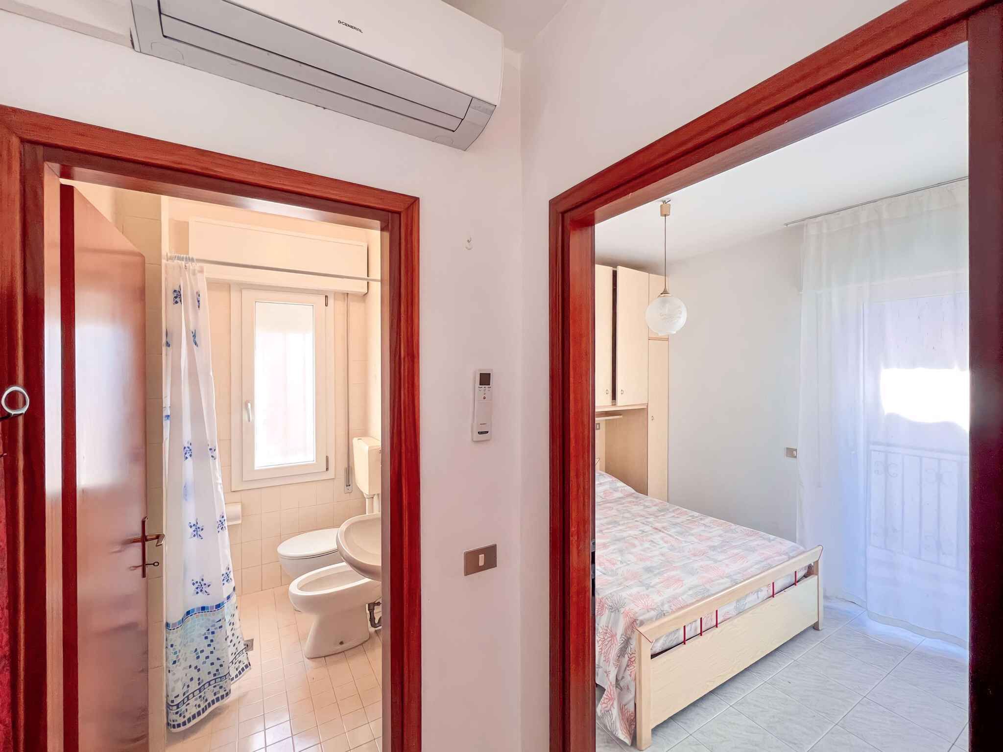 A bedroom with a bed, a bedside table, a wardrobe, and a window with curtains.