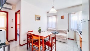 A compact living space with a dining area, a sofa, a kitchen, and a ceiling fan. - Holiday flat with air conditioning (Bibione)