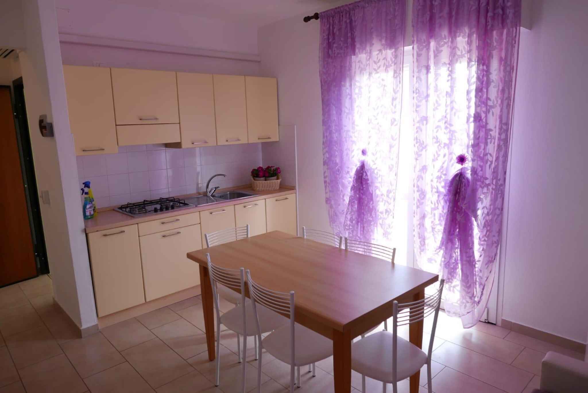 Une cuisine de taille réduite comprenant une table et des chaises, un évier et des placards.