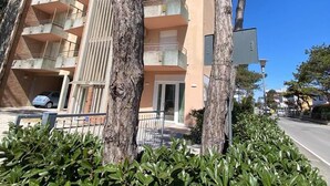 A multi-story building with balconies, a parking area, and a well-maintained garden.