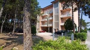 A multi-story building with balconies, surrounded by trees and a parking area. - Holiday apartment with air conditioning (San Michele al Tagliamento)