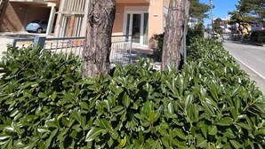 Ein mehrgeschossiges Gebäude mit Balkonen, einer Tiefgarage und einer gepflegten Hecke im Vordergrund.