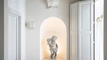 A hallway with white doors, a statue of a child holding a globe, and a decorative wall piece above the statue.
