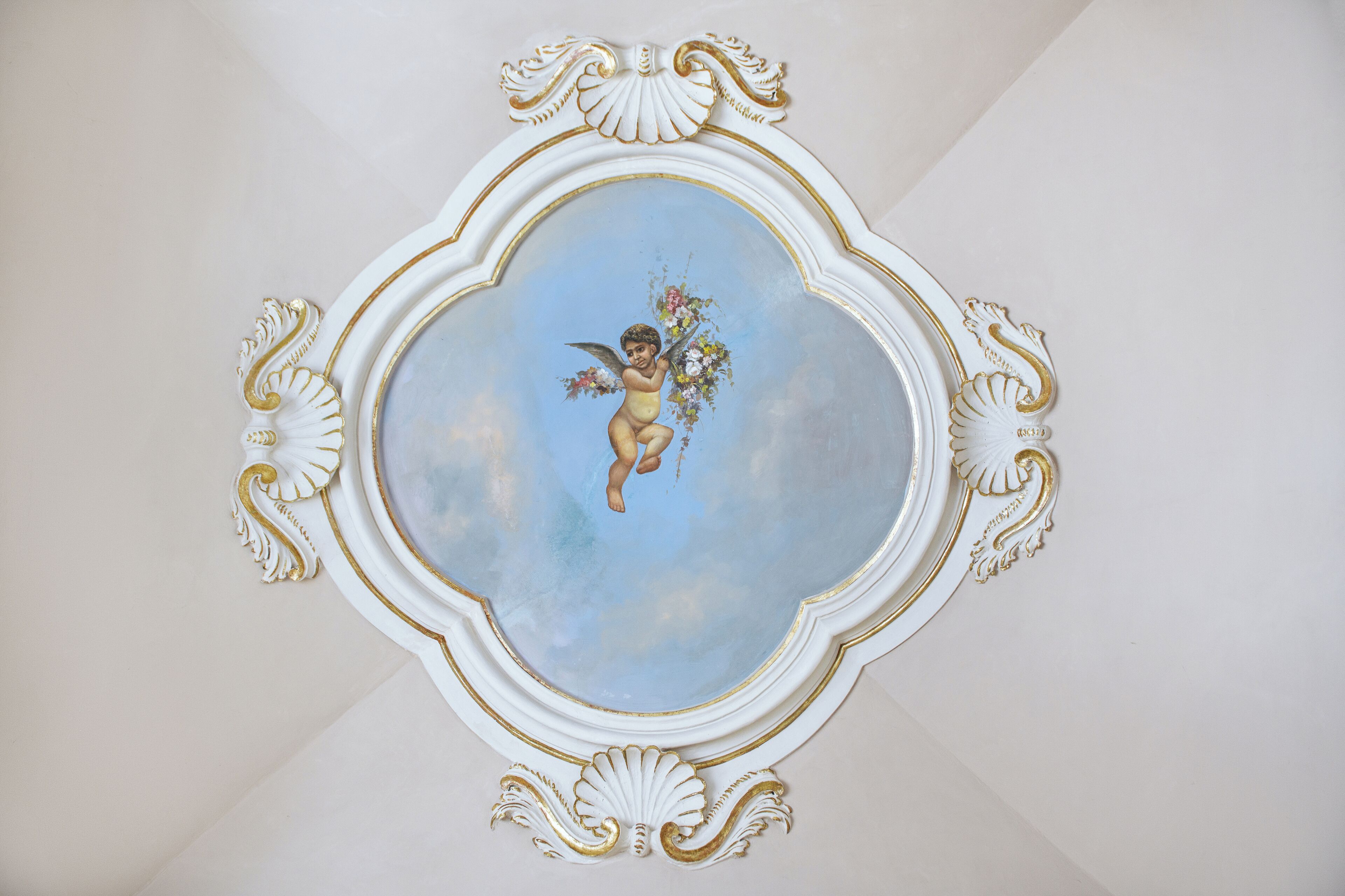 Un techo con un fresco decorativo de un ángel con flores.