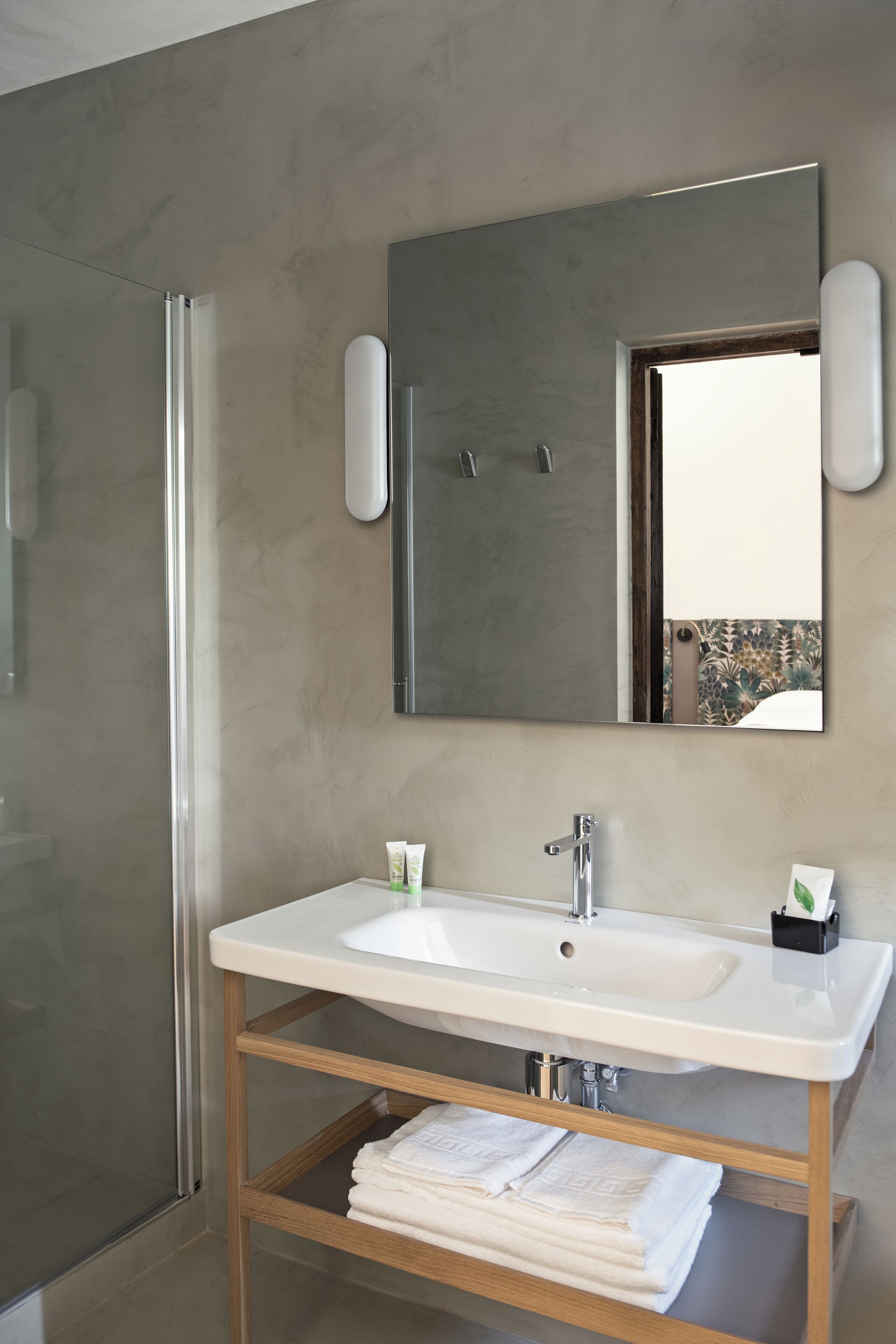 A bathroom with a white sink, a mirror, and a glass shower enclosure.