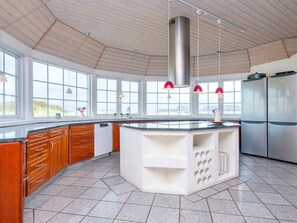 Une cuisine moderne dotée d’un îlot central, de grandes fenêtres et d’appareils électroménagers en acier inoxydable.