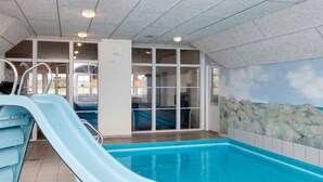 An indoor swimming pool with a blue slide, clear glass walls, and a mural of a beach scene. - 4 Star Holiday Home in Harboore (Harboore)