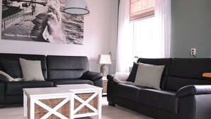 En moderne stue med en sort lædersofa, et hvidt sofabord og en vægmonteret lampe.
