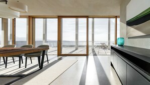 Une cuisine moderne dotée d’une grande porte-fenêtre coulissante qui donne sur un balcon offrant une vue sur la mer.