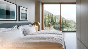 Une chambre à coucher moderne avec un grand lit, une vue sur un paysage montagneux et deux œuvres d’art encadrées accrochées au mur.