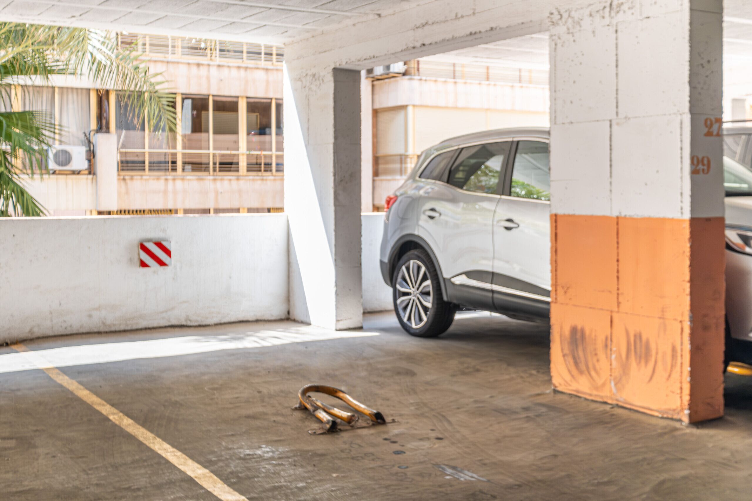 Un parcheggio sotterraneo con un'automobile bianca parcheggiata sotto una colonna di cemento.