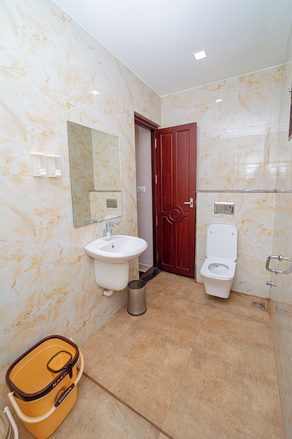 A bathroom with marble walls, a sink, a toilet, and a wooden door. - Magan Enclave (Tarangambadi)