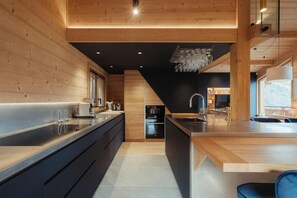 Cozinha moderna com paredes de madeira, uma ilha central e área de jantar com vista.