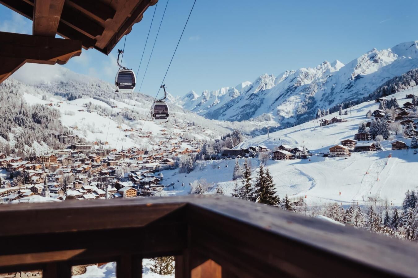 A ski lift with cabins moving over a snowy mountain landscape.