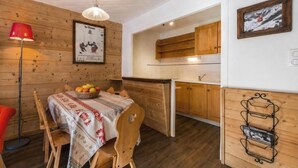 A wooden interior with a dining table, chairs, a red lamp, a framed picture, and a kitchen area. - 300m from ski slopes, 2nd floor, view mountain, balcony, fireplace or stove, tv, ski locker, 53m² (La Clusaz)