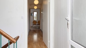 Un estrecho pasillo con suelo de madera que conduce a un comedor con dos sillas y una mesa.