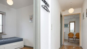 Una habitación con cama, escritorio y silla. Cuenta con una ventana con persianas y un cuadro en la pared.