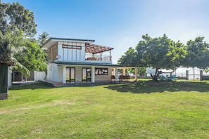 Ett modernt hus i två våningar med en täckt uteplats och en gräsmatta.