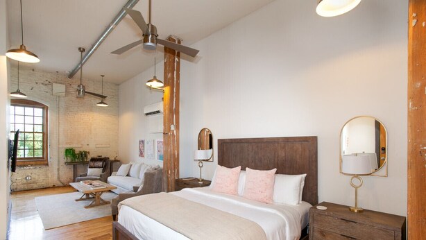 Une chambre spacieuse avec un grand lit, une tête de lit en bois et des tables de chevet équipées de lampes.