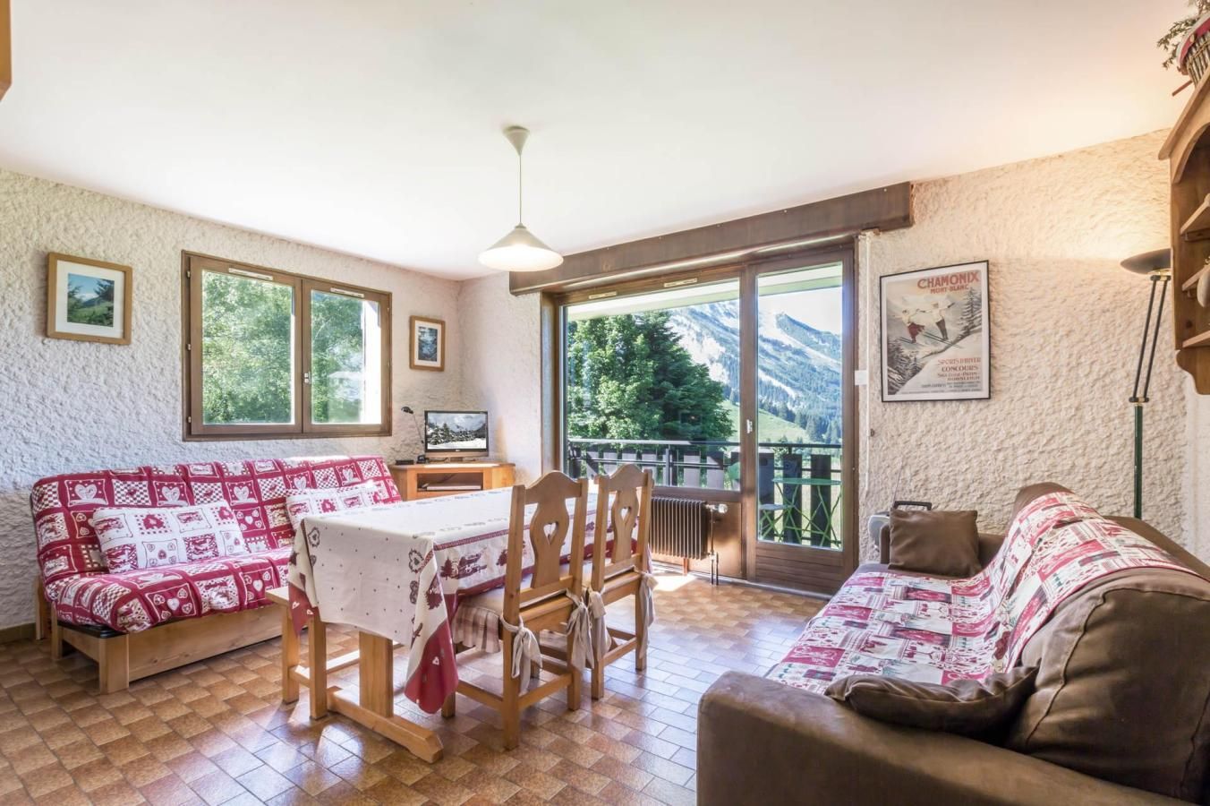 A cozy room with a wooden dining table, two sofas, and a TV.