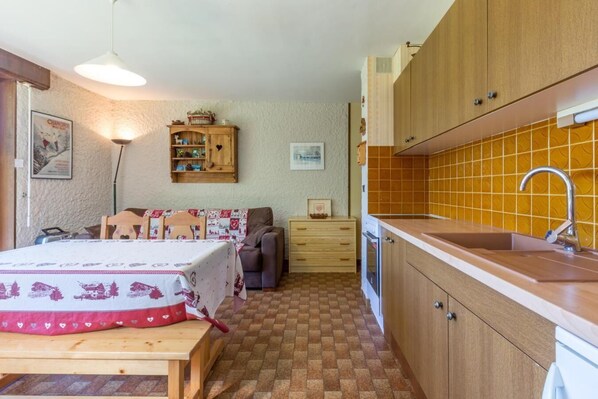 Ein kleiner Raum mit einem Bett, einer Schlafcouch, einem kleinen Tisch, einem Holzschrank, einem Waschbecken und einer gefliesten Rückwand.