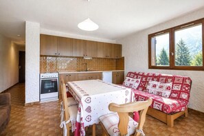 A compact kitchen with wooden cabinets, a white stove, and a dining table with a red and white tablecloth.