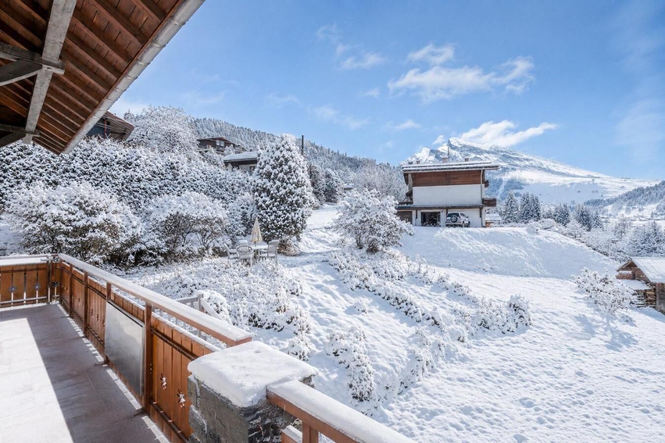 Paisaje nevado con una terraza de madera y un edificio de diseño moderno.