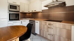 Eine moderne Küche mit Edelstahlgeräten, einem Holzespeisetisch und hellen Küchenschränken.