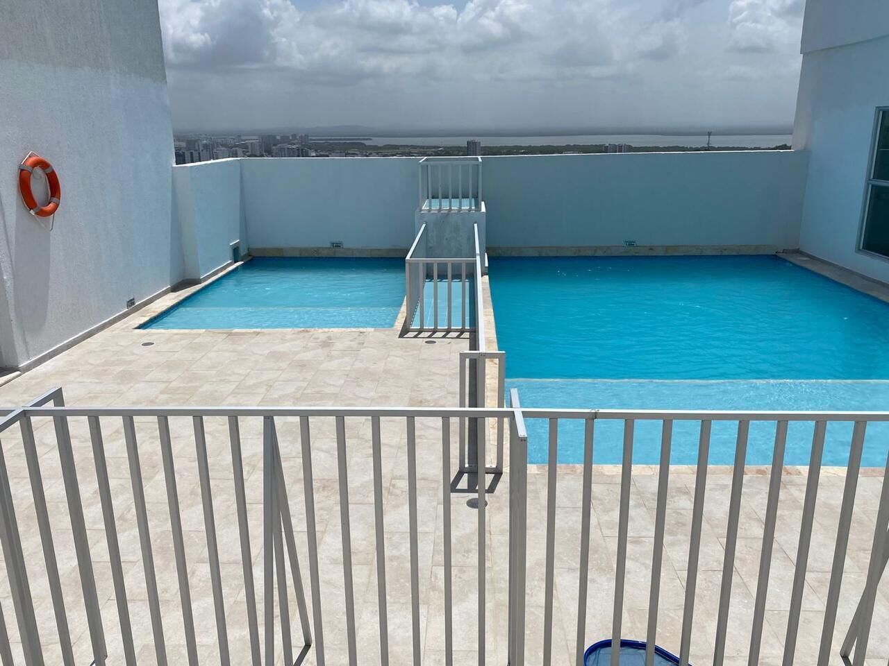 A rooftop swimming pool with a clear view of the city skyline.
