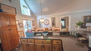 A kitchen with wooden cabinets, a granite countertop, and a dining area with chairs.