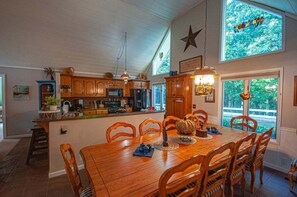 A spacious kitchen with wooden cabinets, a central island, and a dining area with a large table and chairs. - Bearadise Ridge-Hot tub-Firepit (Blairsville)